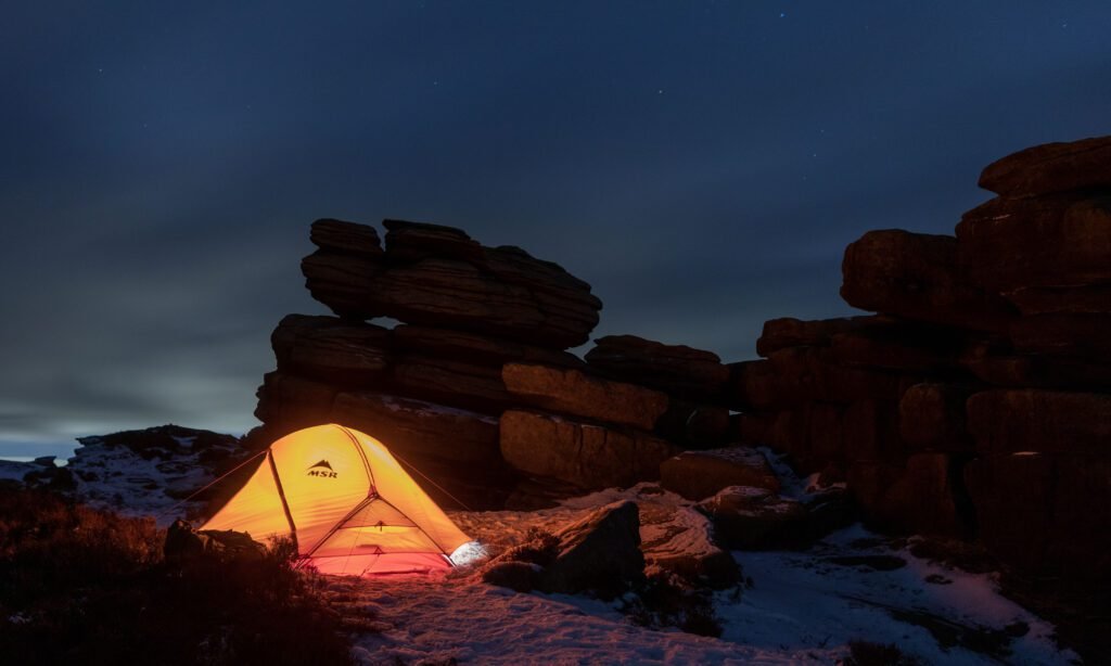 MSR Access 2 lit from inside among gritstone rocks in the Peak District at dusk