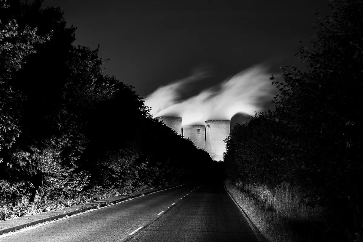 Road leading towards the Drax cooling towers at night with steam rising, black and white