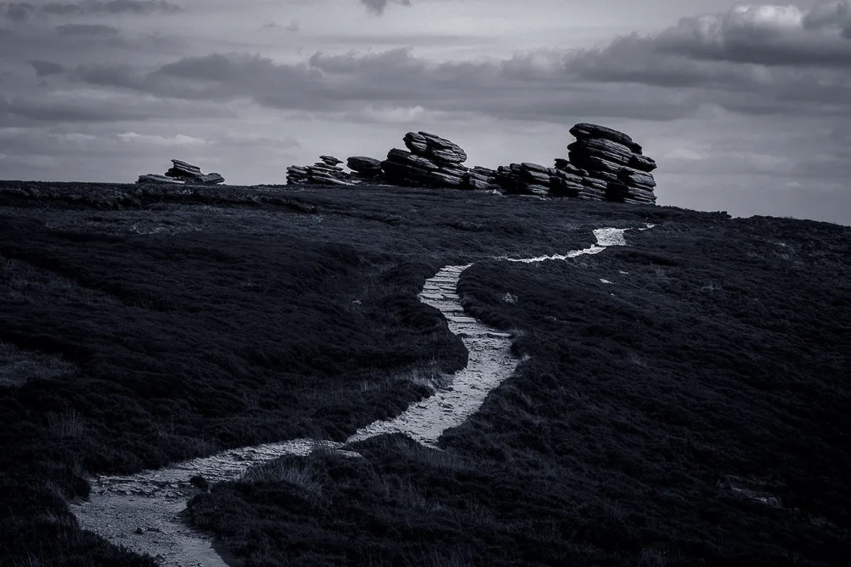 The path along Derwent Edge between gritstone outcrops in black and white